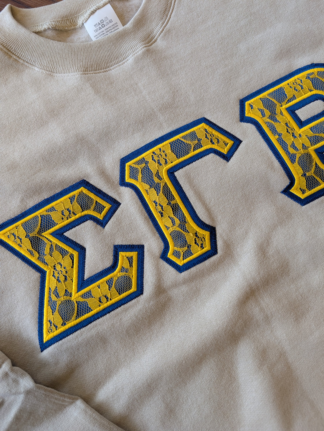 White sweatshirt with blue and yellow letters on a gray background