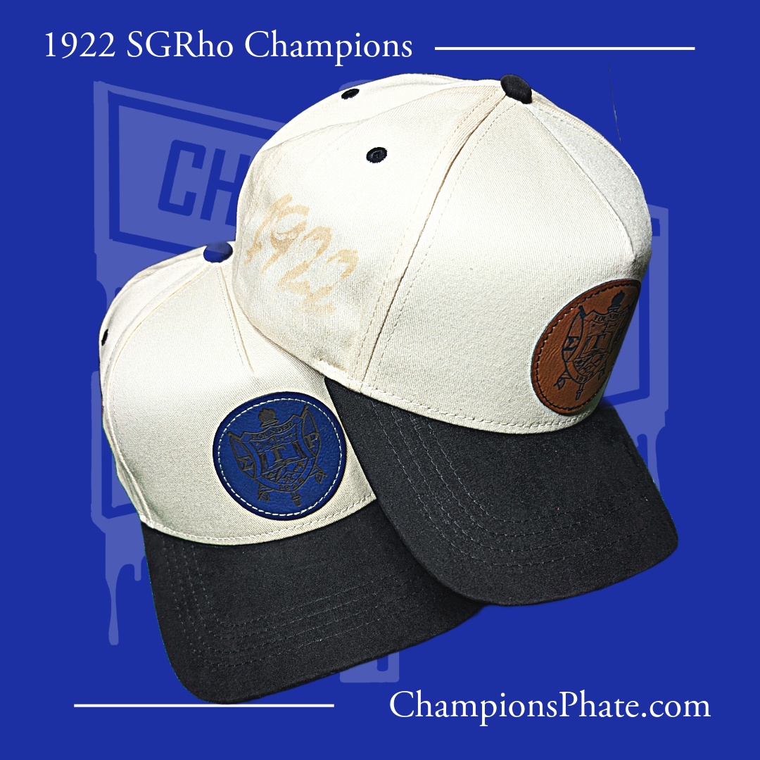 Two A-frame caps with suede brim and top button, one featuring a blue and the other a brown patch, set against a blue background with '1922 SGRho Champions' text.