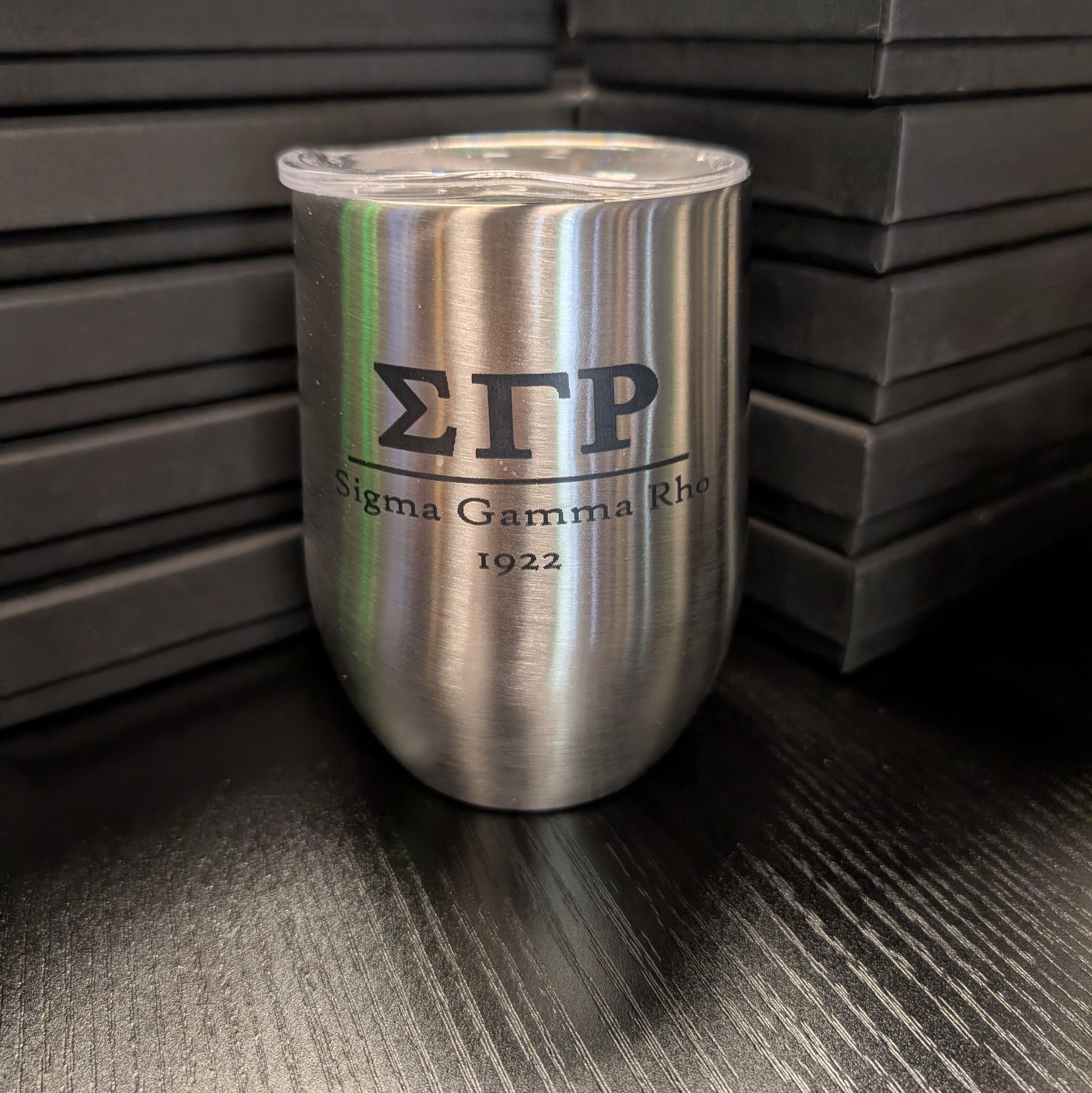 Silver tumbler with 'Sigma Gamma Rho 1922' text on a dark surface