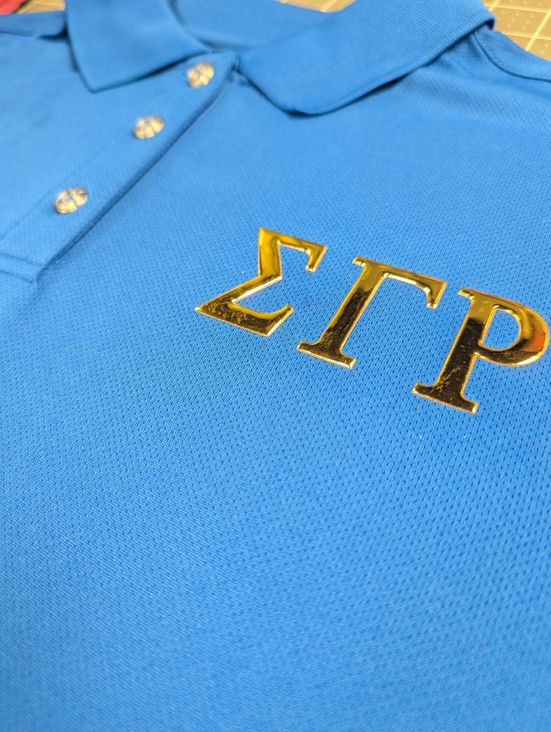 Blue polo shirt with gold greek letters for sigma gamma rho sorority