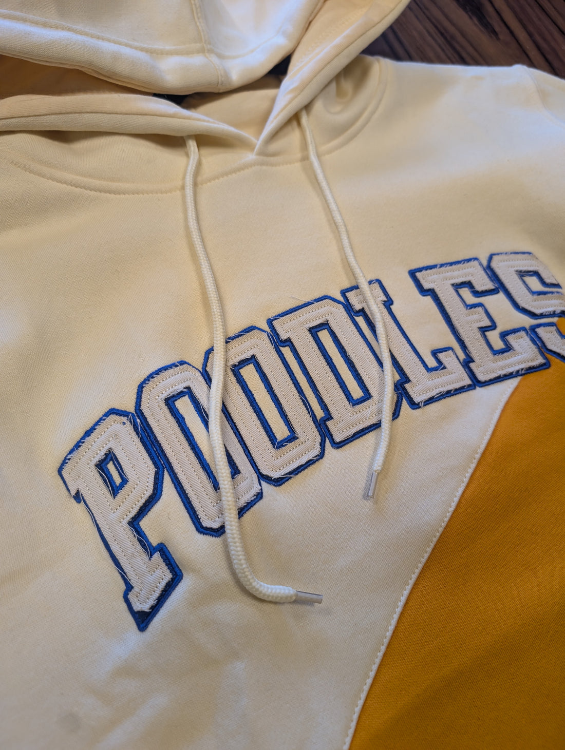 cream and yellow hoodie with "poodles" written on chest
