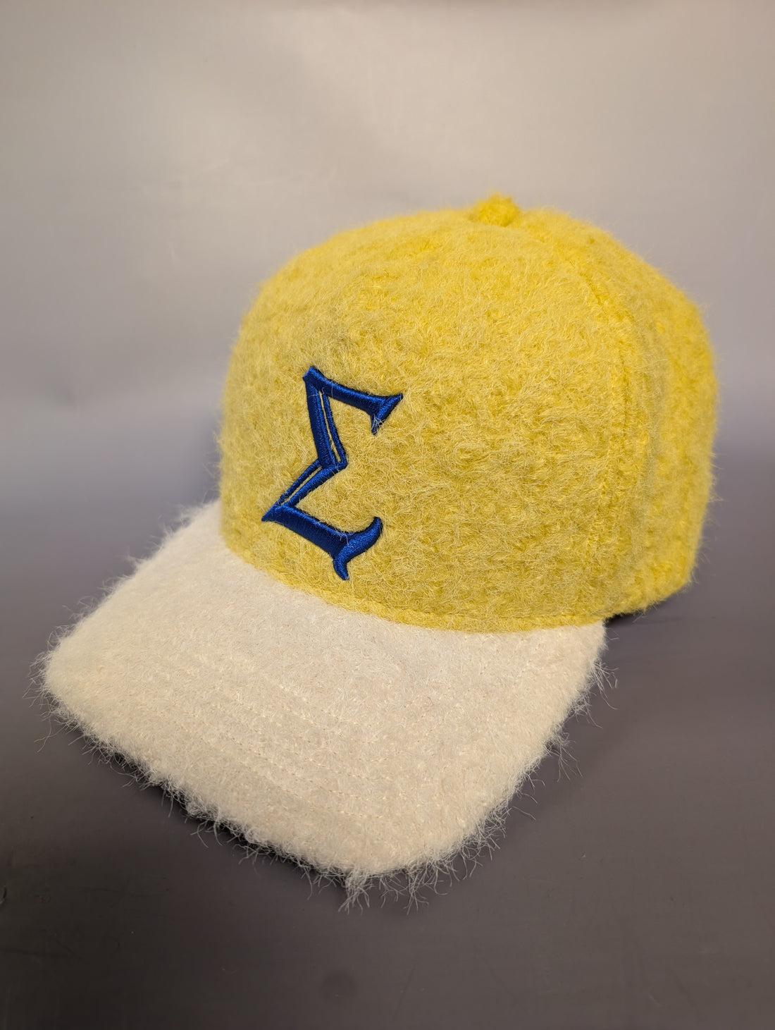 Yellow and cream hat with a blue sigma embroidered on it