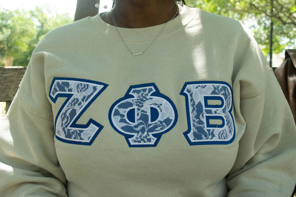 Person wearing a light-colored sweatshirt with 'Zeta Phi Beta' letters.