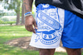 Person wearing blue shorts with a white emblem in an outdoor setting