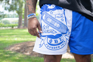 Person wearing blue shorts with a white emblem in an outdoor setting