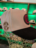 Beige and black cap with SEC logo on a mannequin head against a green background