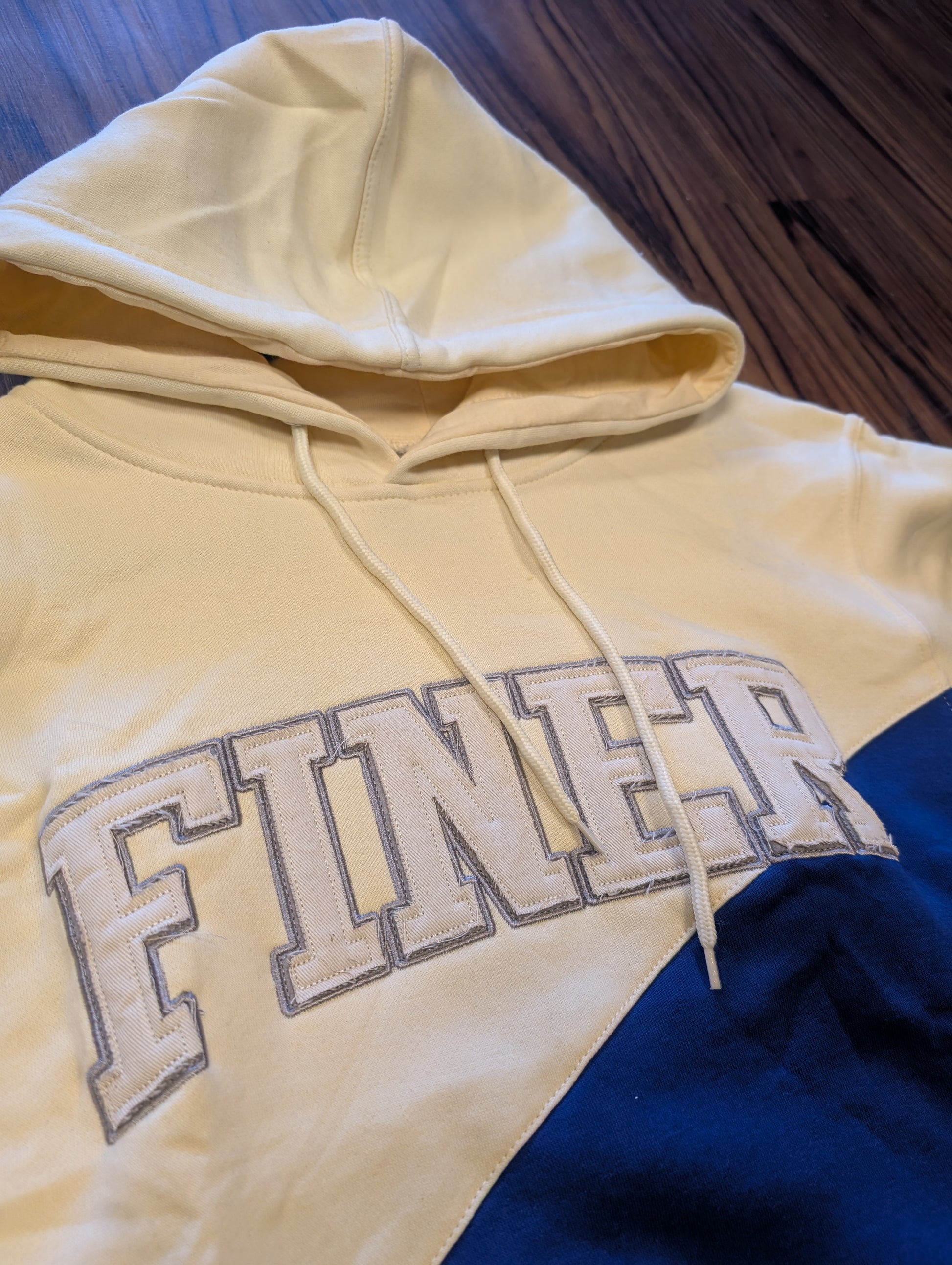 cream and blue hoodie with the word "finer" on chest