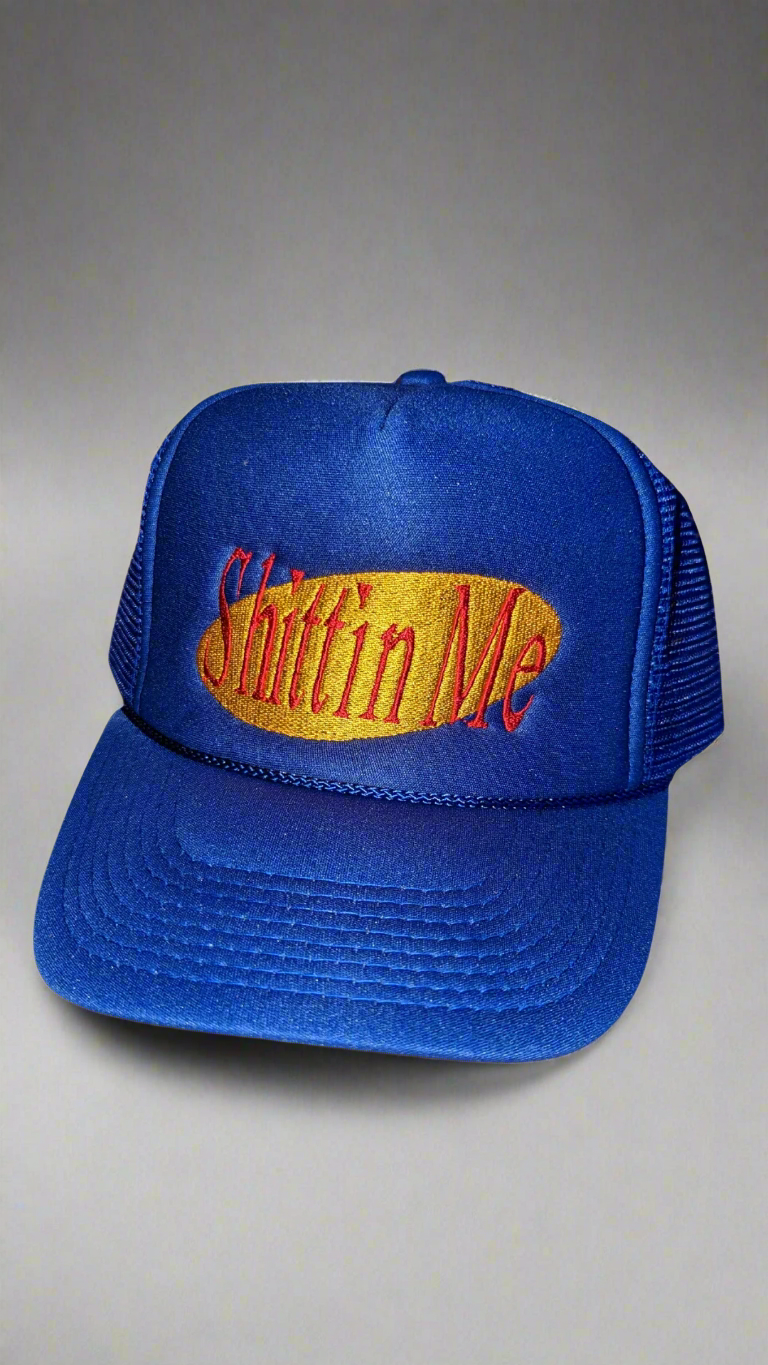 Blue trucker hat with 'Shittin Me' text in red and yellow in Seinfeld font
